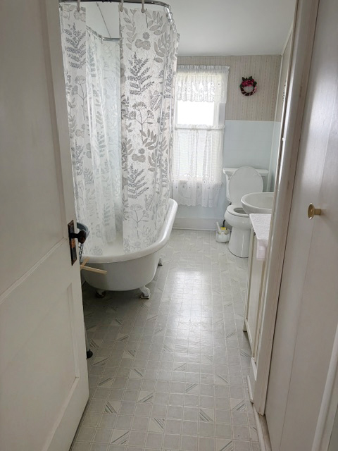 A well maintained vintage bathroom includes a claw foot tub with shower.